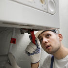 Technician cleaning a clogged outdoor drain filled with sand and debris in Abu Dhabi.